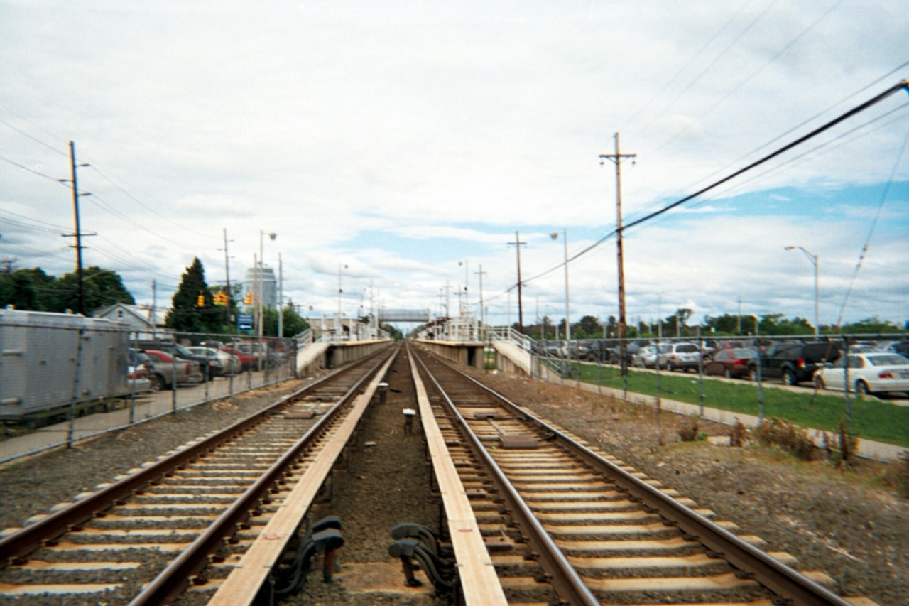 Long Island Rail Road tracks leading west into Deer Park station, with commuter parking lots on both sides