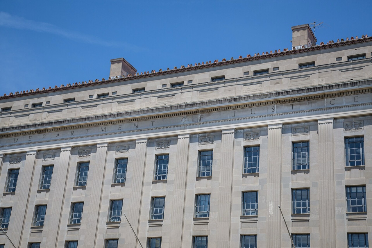 Limestone facade of the U.S. Department of Justice building in Washington with its carved name under blue sky